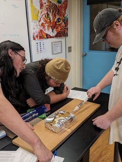 Three male Rock Point School students work together in science class on a hands-on experiment.