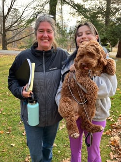 The Dean of Rock Point School stands with a student outside on campus at in Burlington, VT. The student holds up and poses with one of the campus dogs.