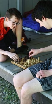 Two Rock Point School students engage in a game of chess during their annual camping trip, inside one of the lean-to buildings.