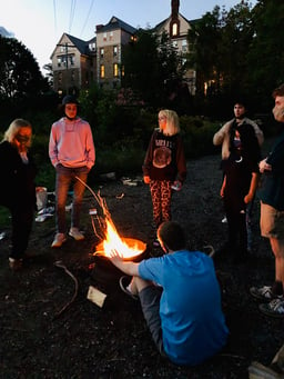 Teens making s'mores around a summer camp fire