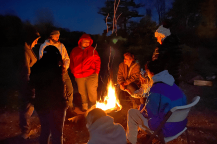 a group of teens gathered around a campfire in the winter