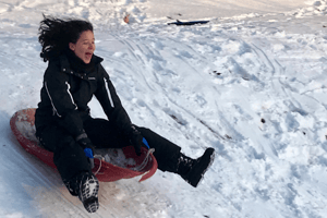 teen sledding down a hill