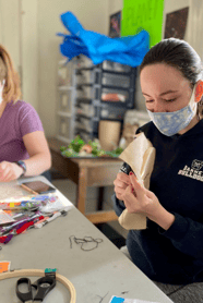 A teen in a mask doing arts and crafts