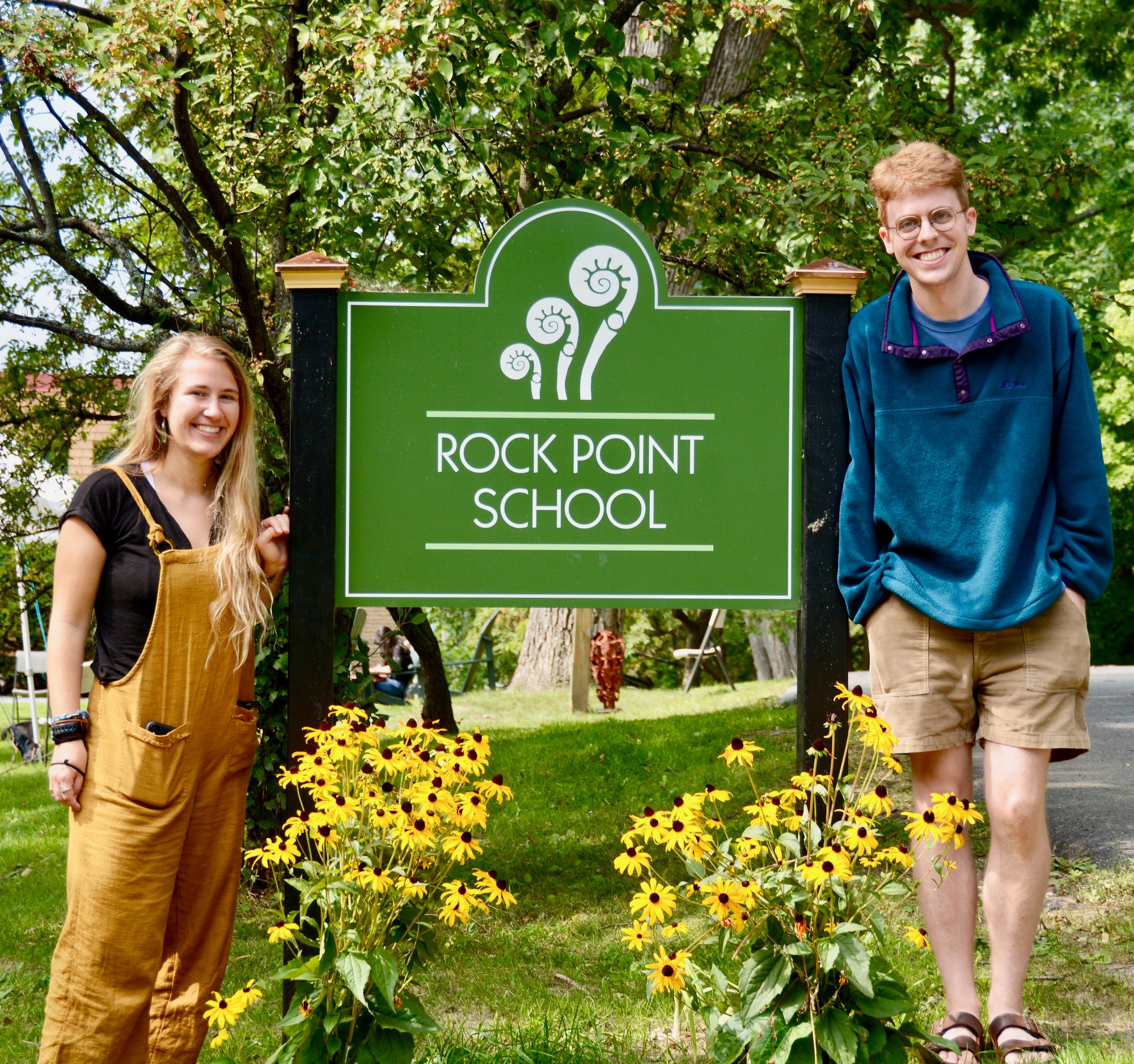 Rock Point School sign with two students standing