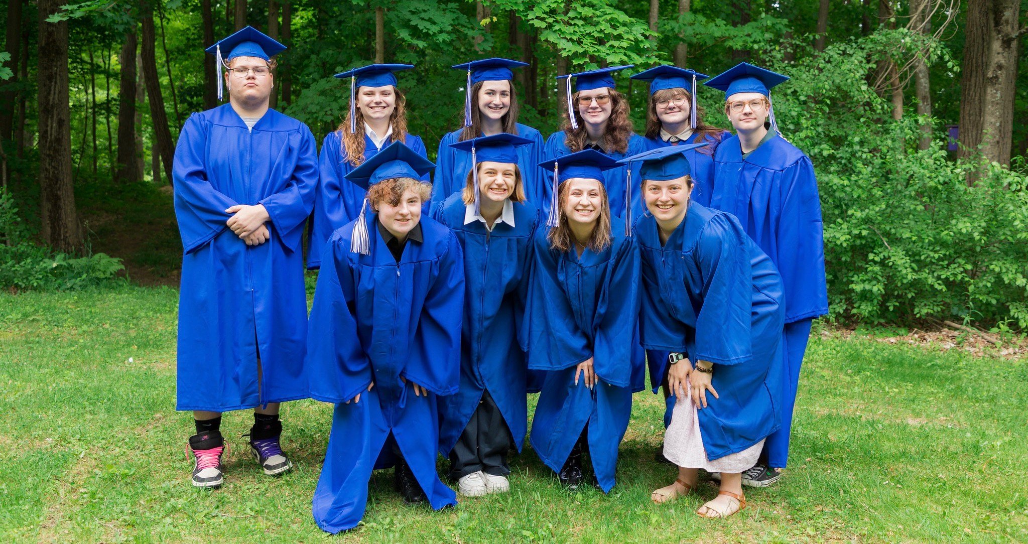 The class of 2023 wearing blue caps and gowns and smiling