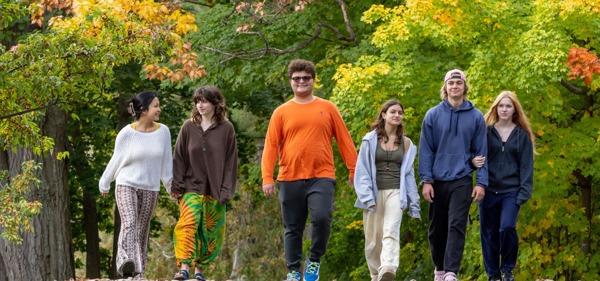 6 Rock Point School students walk along the path lined with trees on school grounds.