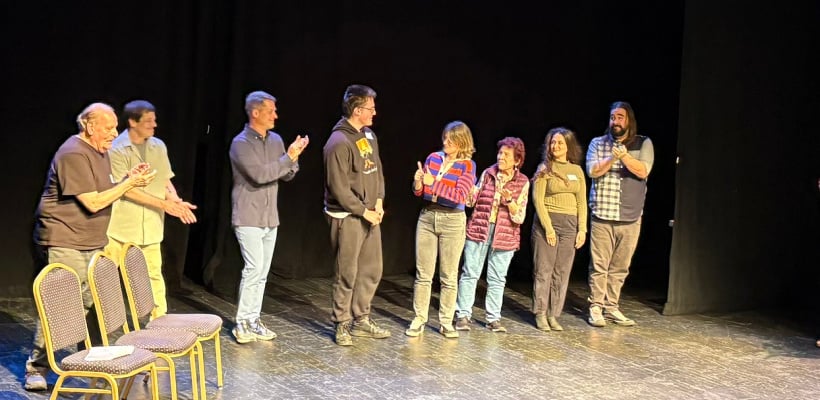 A Rock Point Student standing on stage with the actors who performed his play