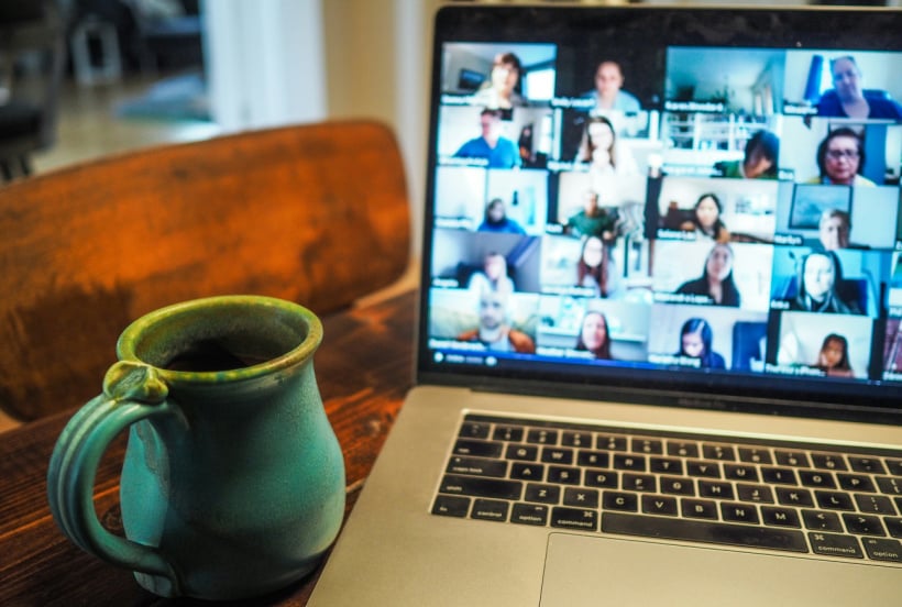 A blue mug and a laptop with a zoom meeting on the screen